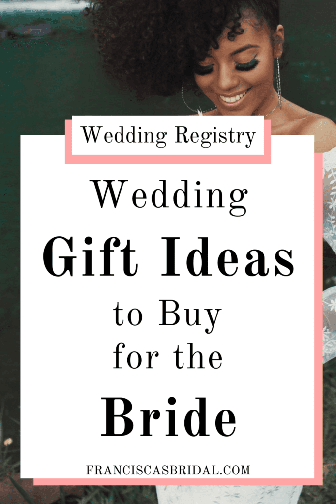 A bride holding her flower bouquet while standing in front of a lake with text over the photo that says wedding gift ideas for the bride.