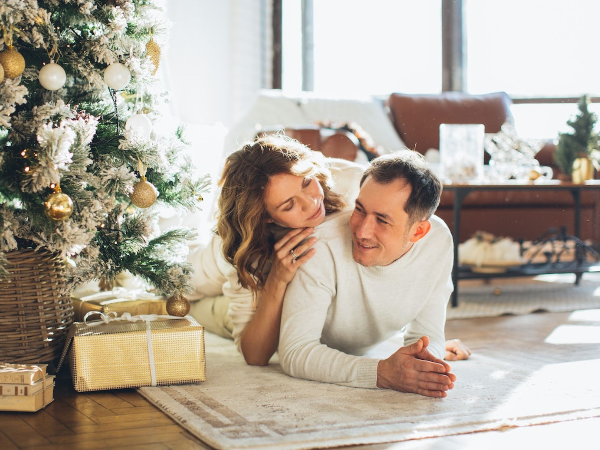 A couple laying under the Christmas tree.