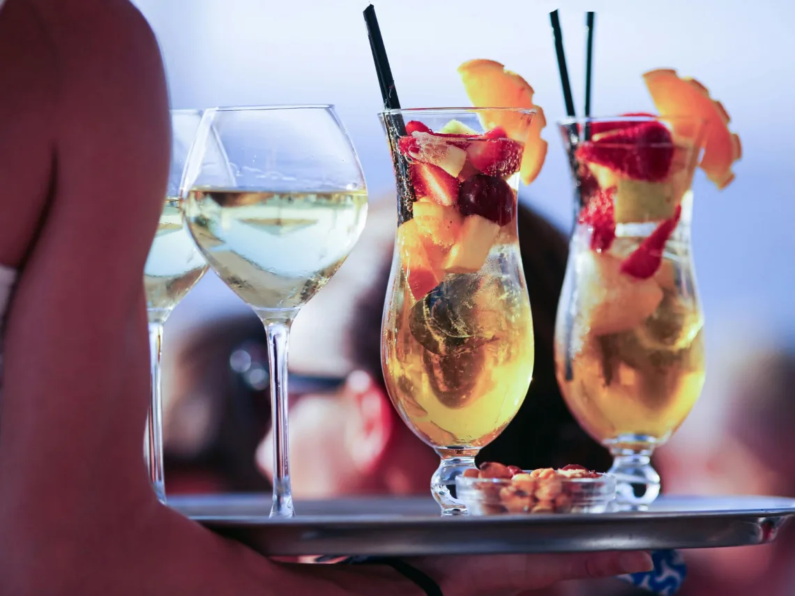 A woman carrying a tray of fruit wedding cocktails.