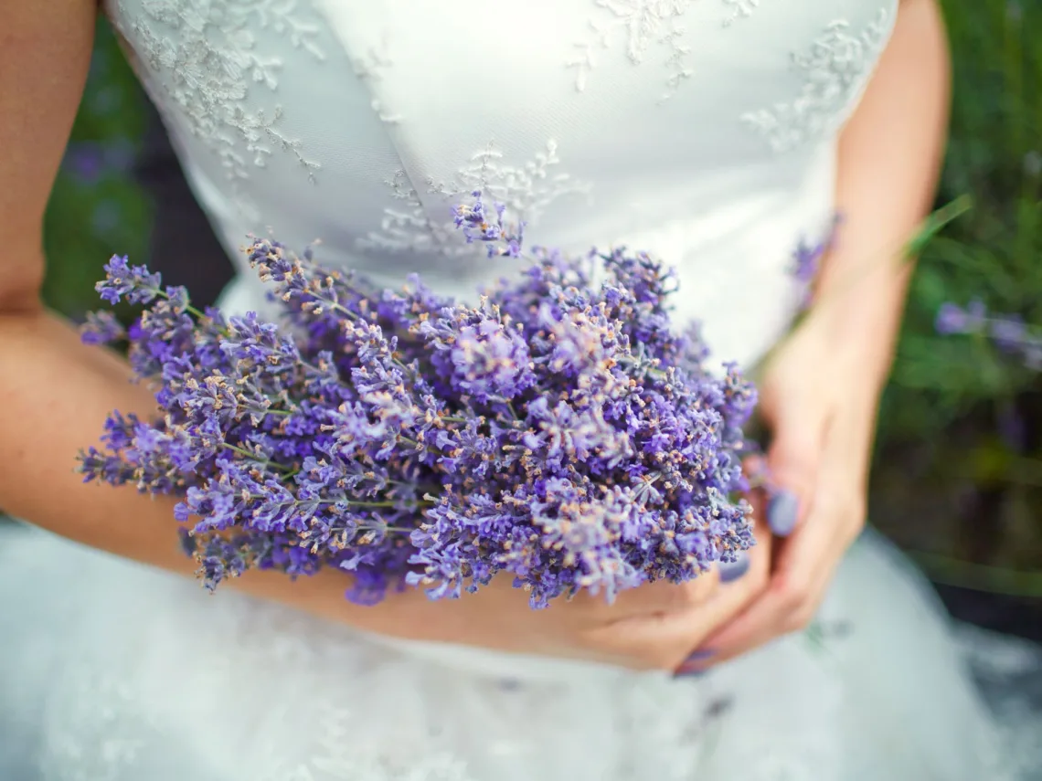 A bride holding a lavender wedding bouquet.