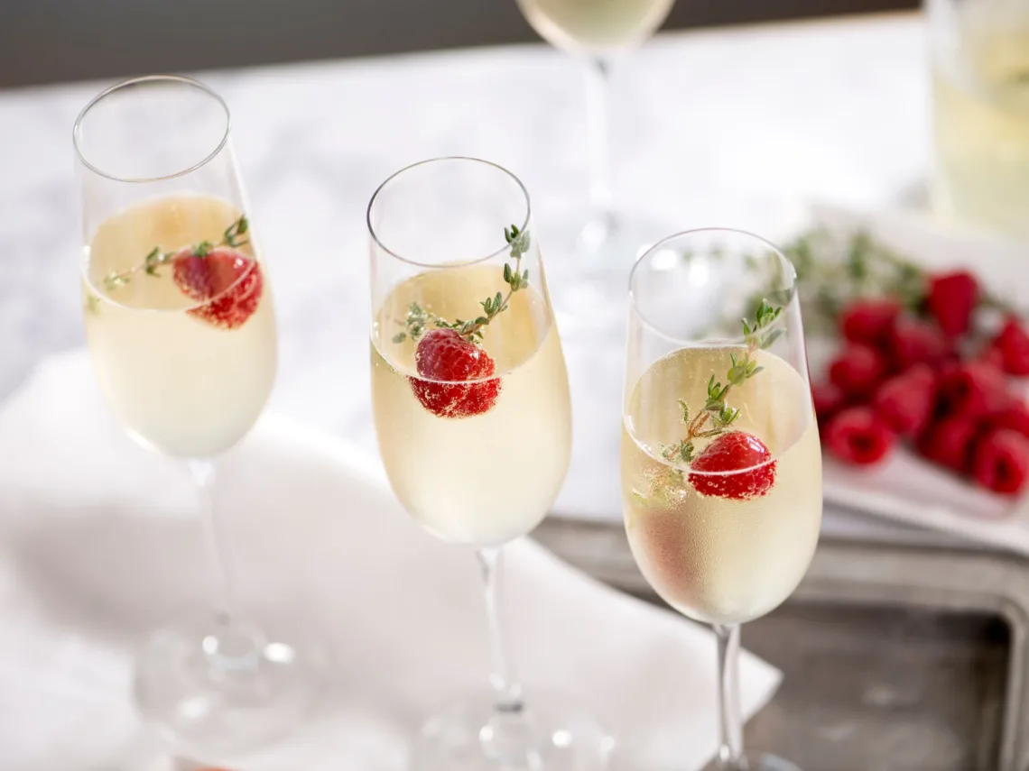 A glass of champagne with fresh raspberries in them.
