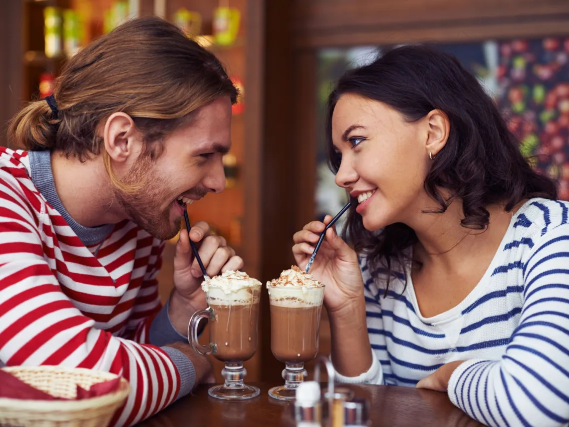 A couple sharing a chocolate milkshake.